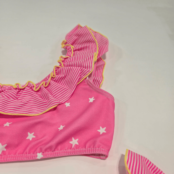 Confeccionadas en una tela elástica y cómoda, ideal para el baño. El bikini presenta un diseño en color rosa con pequeños patrones de estrellas blancas, que añaden un toque divertido y juvenil.