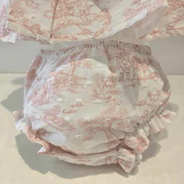 Este Jesusito se presenta con tirantes finos ideal para un look ligero y fresco. El cuerpo del top presenta un pequeño nido de abeja sobre tela rizada que proporciona elasticidad a la vez que decorativo. Los bordes de los bloomers están adornados con volantes que les da un aire juguetón. puedes apreciar un cuidado especial en los remallados y las terminaciones, se presentan ambas piezas en diseño toile de youy y es de la campaña primavera verano de la firma Martín Aranda.