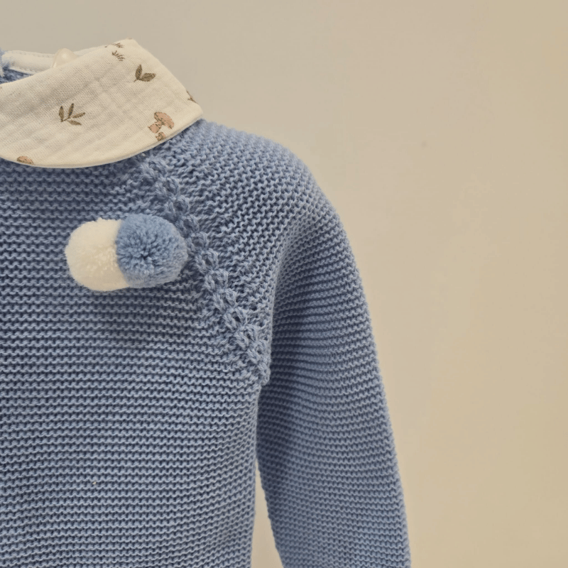 Conjunto Juliana invierno con jersey azul de punto y pompón decorativo. Cuello bebé estampado y braga de tela con motivos naturales. Cálido, dulce y perfecto para la temporada fría.
