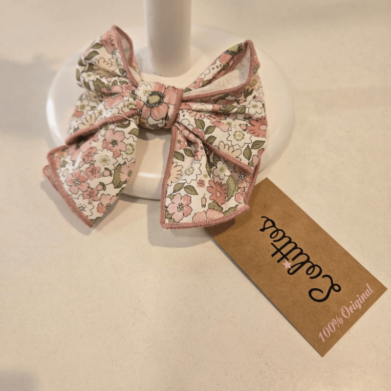 Este lazo de la colección Bubú de Lolittos está elaborado en una tela floral de tonos rosa, beige y verde, manteniendo la estética clásica y cuidada de la firma. Su ribete delicado aporta definición y un toque coqueto sin recargar el conjunto. Ligero, práctico y fácil de combinar, es el accesorio perfecto para completar los looks de la temporada, aportando ese gesto final que ilumina el estilismo con suavidad.